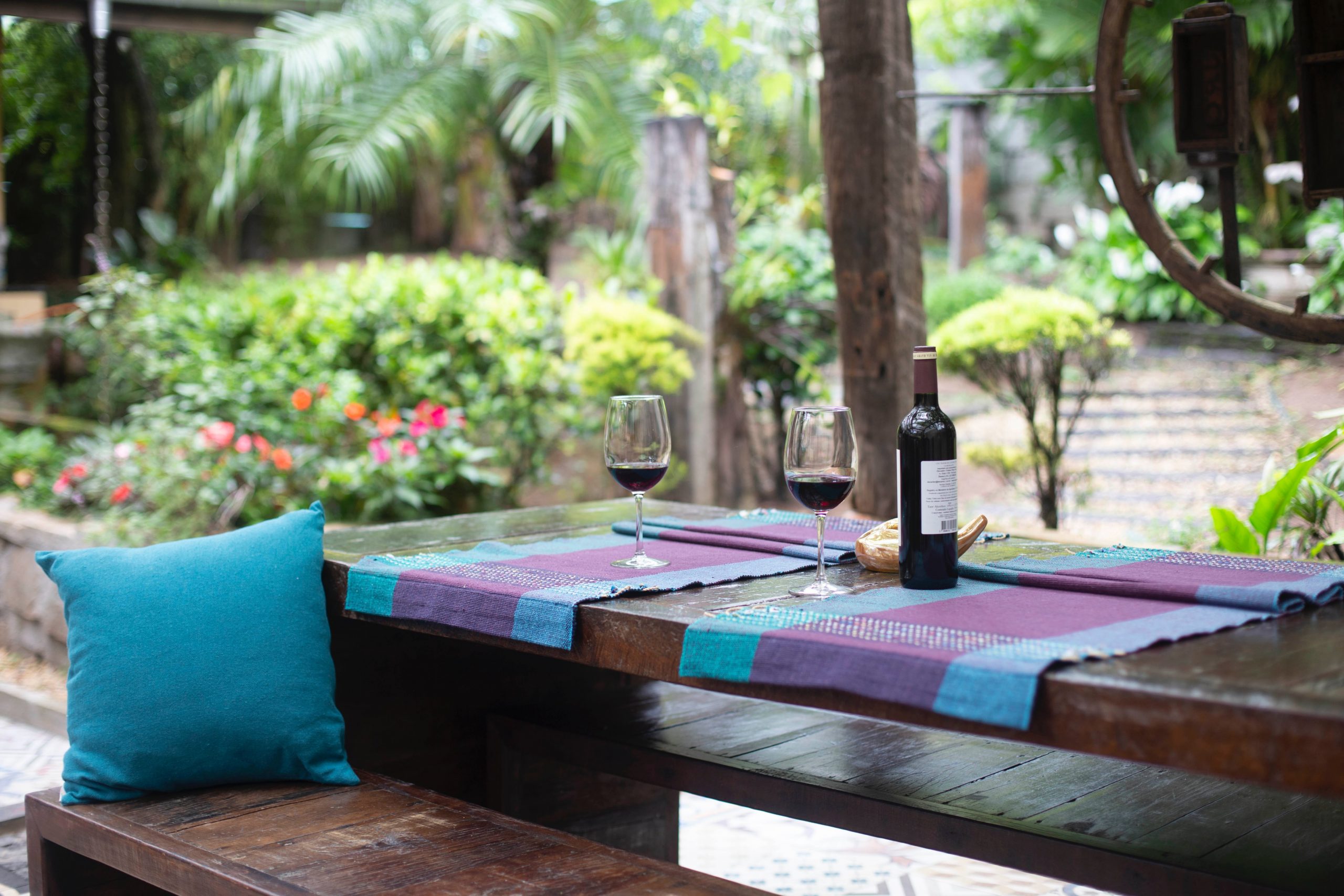 Table and benches with wine bottle and glasses in landscaped patio